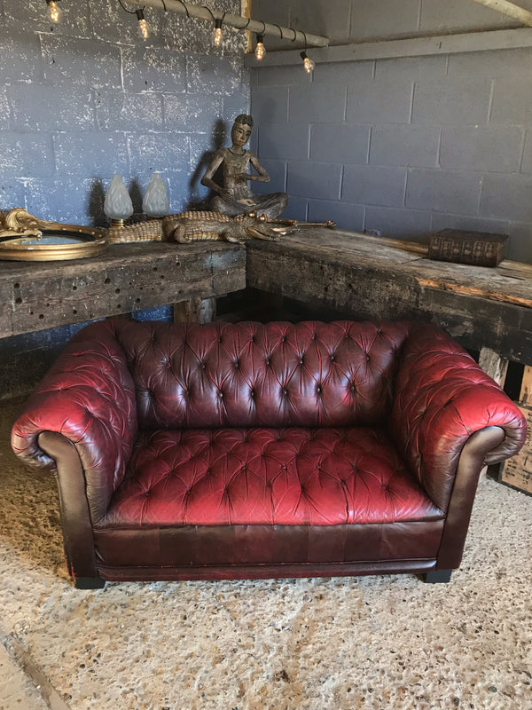 An oxblood two seater Chesterfield sofa with button back and seat