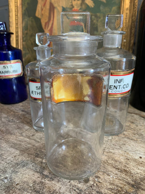 A collection of three clear glass apothecary bottles
