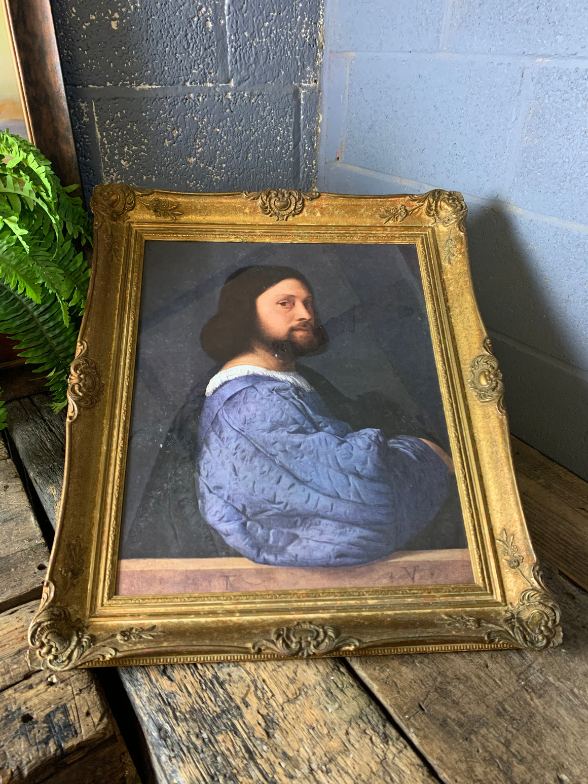 A large framed print of Titian's "Portrait of a Man"