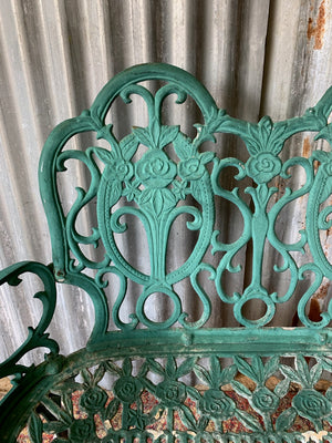 A green cast metal rose motif garden bench