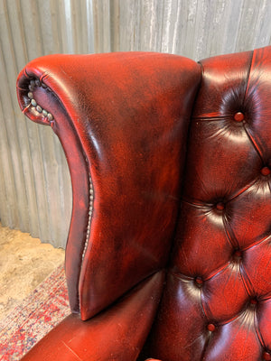 An oxblood wingback Queen Anne-style armchair