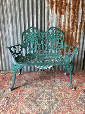 A green cast metal rose motif garden bench