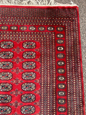 A large red ground Bokhara rectangular rug ~ 282cm x 186cm