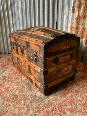 An oak dome top steamer trunk with tooled leather motifs