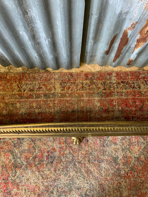 A large Victorian brass fender with lion paw feet