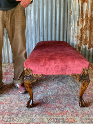 A large red velvet ball and claw footstool