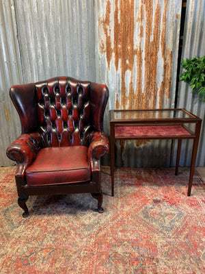 An oxblood wingback Queen Anne-style armchair