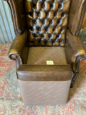 A brown wingback Chesterfield armchair with button back