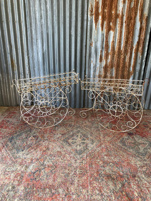 A pair of white wirework barrow plant stands