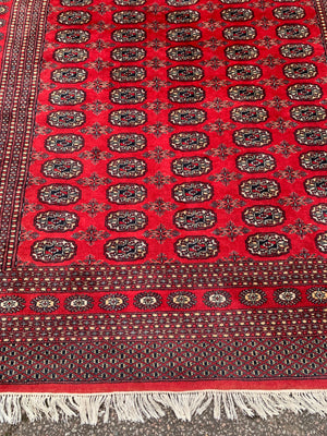 A large red ground Bokhara rectangular rug ~ 282cm x 186cm