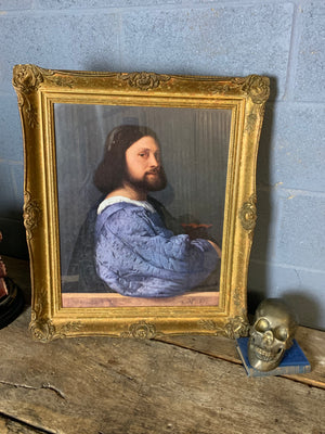 A large framed print of Titian's "Portrait of a Man"