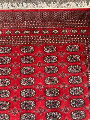 A large red ground Bokhara rectangular rug ~ 282cm x 186cm