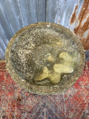 A cast stone cherub bird bath