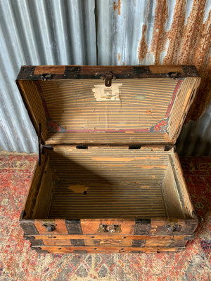 An oak dome top steamer trunk with tooled leather motifs