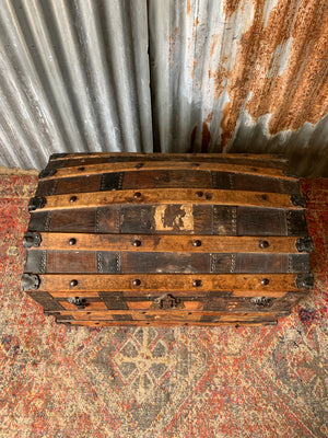 An oak dome top steamer trunk with tooled leather motifs