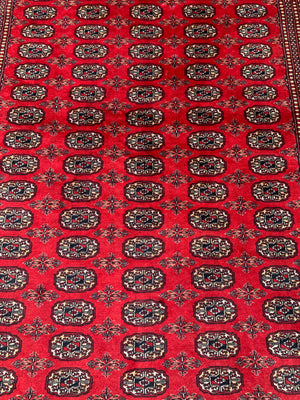 A large red ground Bokhara rectangular rug ~ 282cm x 186cm