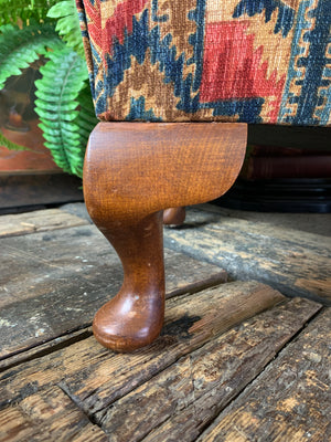 A large kilim-style footstool on cabriole legs