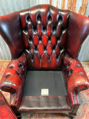 An oxblood wingback Queen Anne-style armchair