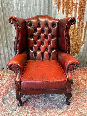 An oxblood wingback Queen Anne-style armchair