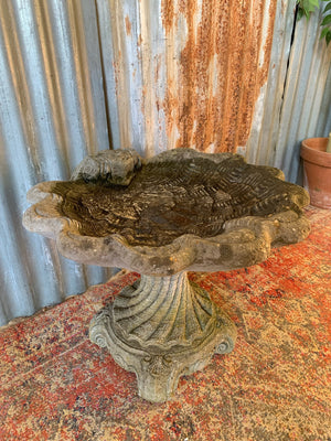 A cast stone bird bath in the form of a shell