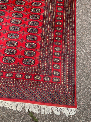 A large red ground Bokhara rectangular rug ~ 282cm x 186cm