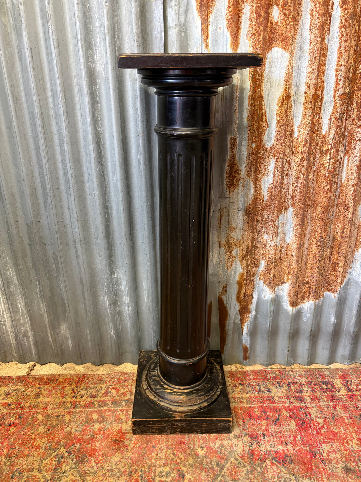 A black wooden pedestal column display stand