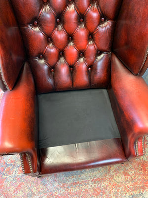 An oxblood wingback Queen Anne-style armchair