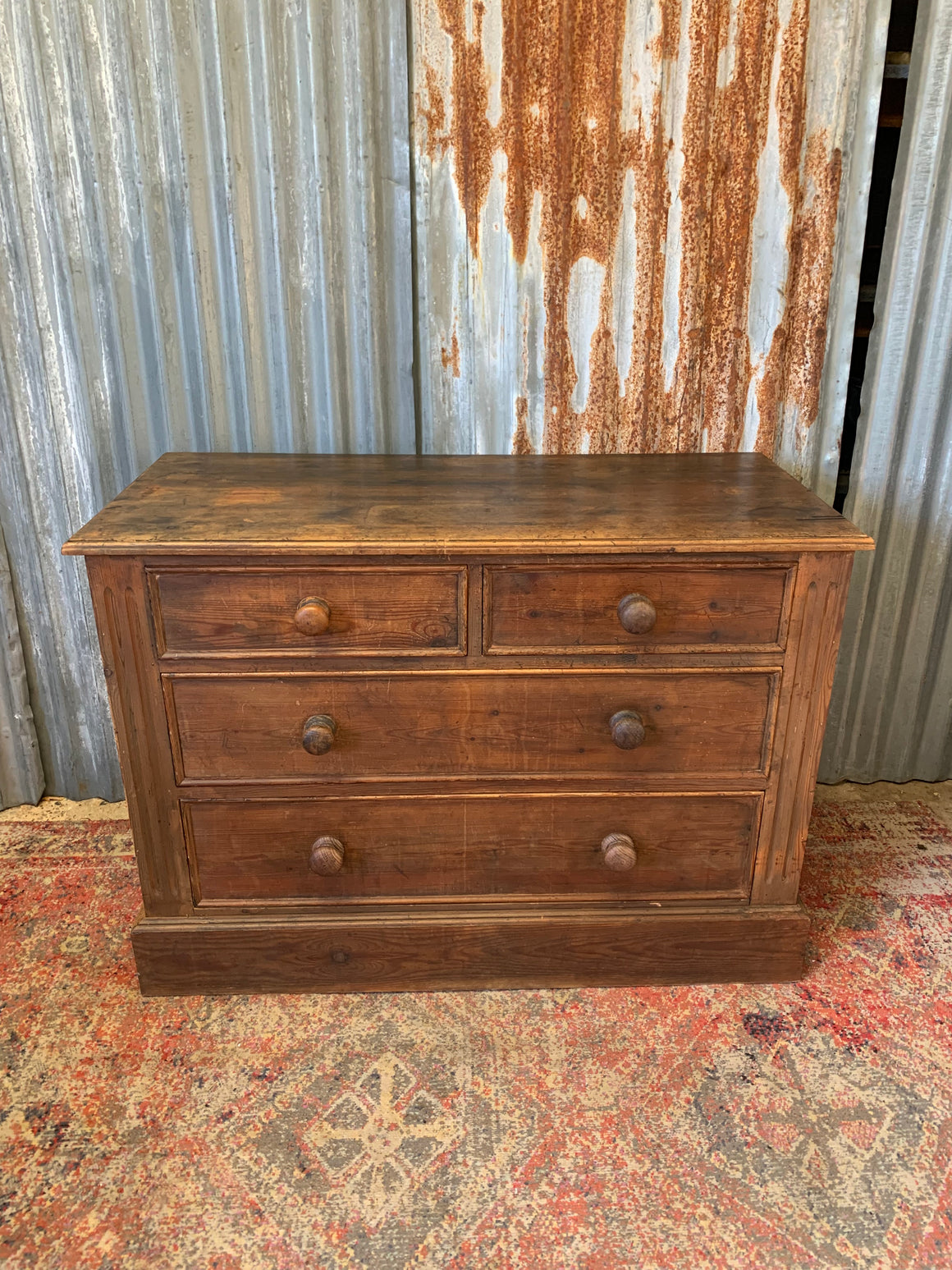 A dark pine chest of four drawers
