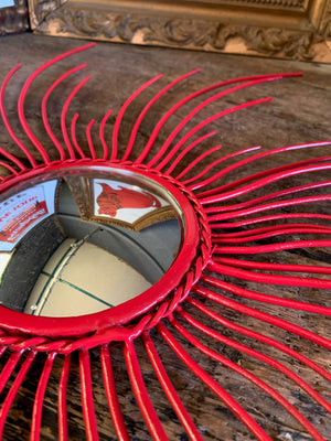 A red metal starburst convex mirror