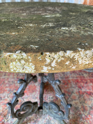 A cast iron garden table with a circular stone top