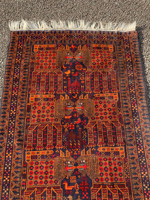 A rectangular red ground Belouch Herat rug depicting lions, camels and birds