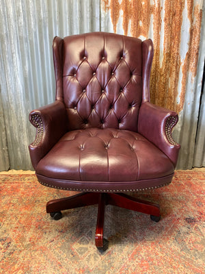 A burgundy leather full button tilt and swivel desk chair