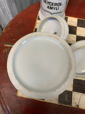 A set of three white ceramic apothecary jars