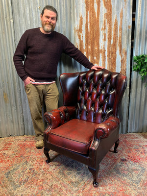 An oxblood wingback Queen Anne-style armchair