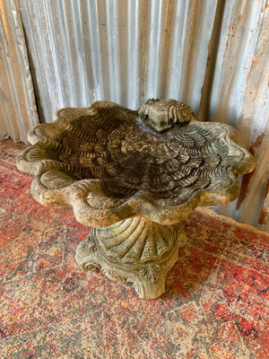 A cast stone bird bath in the form of a shell