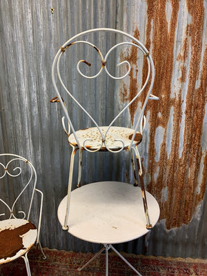 A white French wirework garden set with two chairs and a tripod table