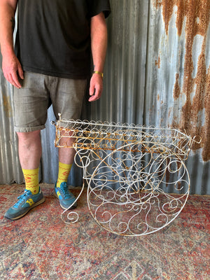 A pair of white wirework barrow plant stands