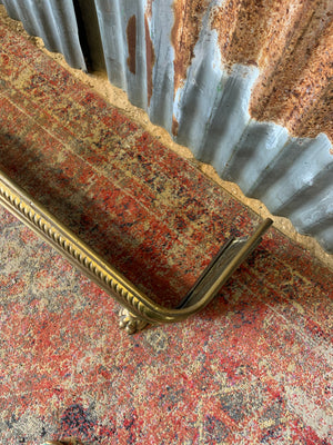 A large Victorian brass fender with lion paw feet