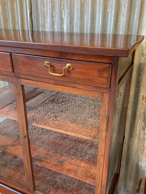 A mahogany double-fronted glass display cabinet with two drawers