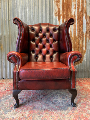 An oxblood wingback Queen Anne-style armchair