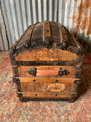 An oak dome top steamer trunk with tooled leather motifs