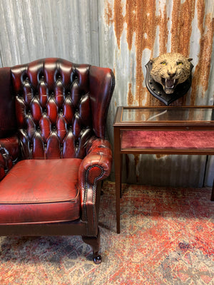 An oxblood wingback Queen Anne-style armchair