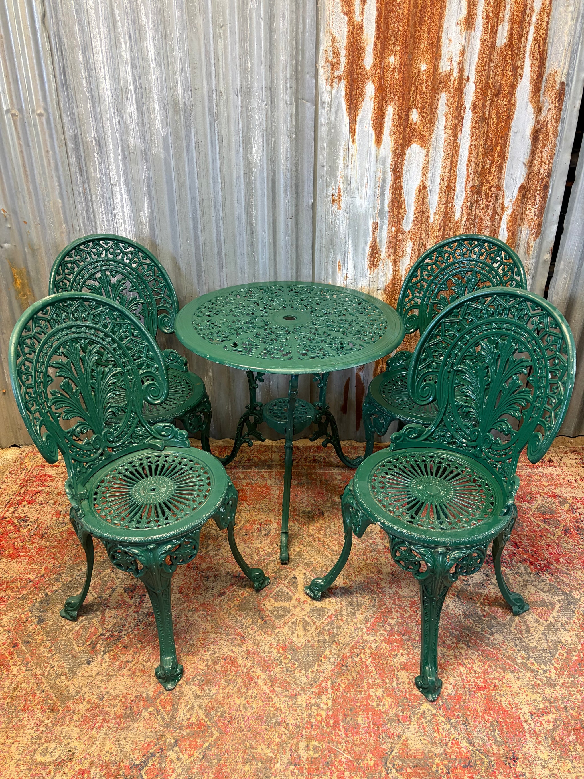 A green garden table and four chair bistro set
