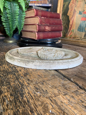 An oval cast stone plaque depicting a dog's head in profile ~A