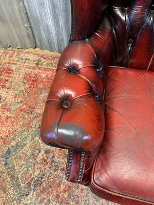 An oxblood wingback Queen Anne-style armchair