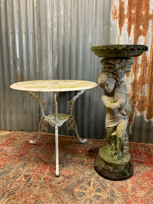 A neoclassical cast stone birdbath with cherub and fish design