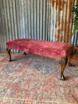 A large red velvet ball and claw footstool