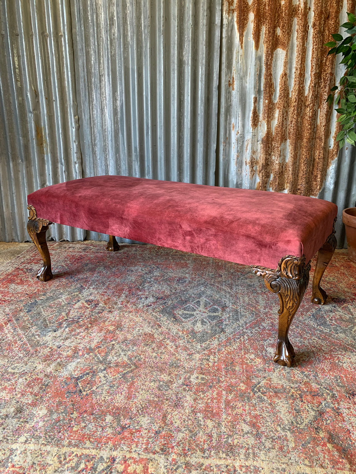 A large red velvet ball and claw footstool