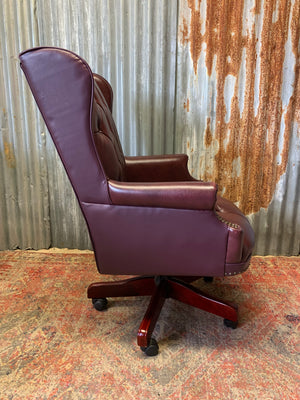 A burgundy leather full button tilt and swivel desk chair