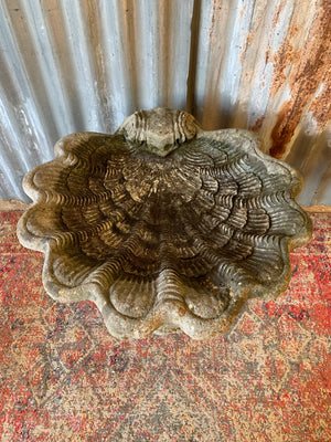 A cast stone bird bath in the form of a shell